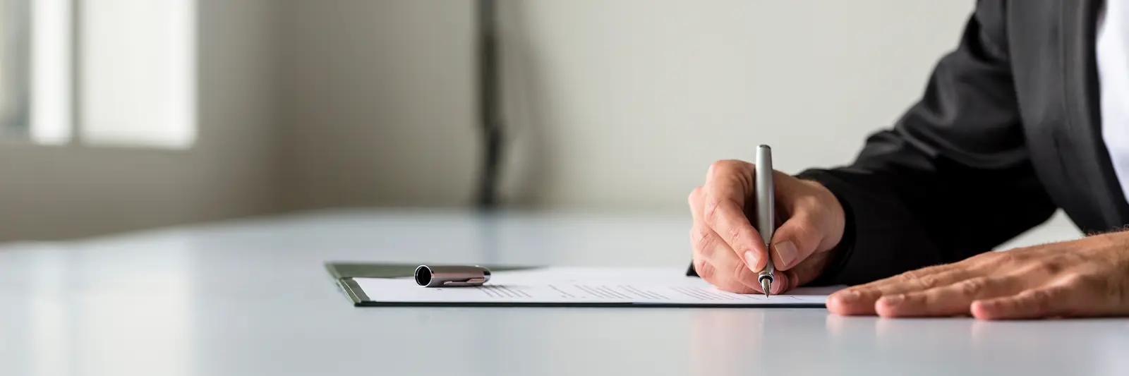 Une personne coche une liste de vérifications avec une calculatrice sur son bureau.